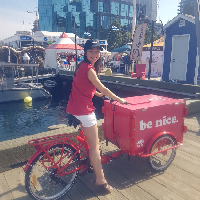 woman smiling while riding a Roots Canada Icicle Tricycle Ice Cream Bike on the Halifax Pier